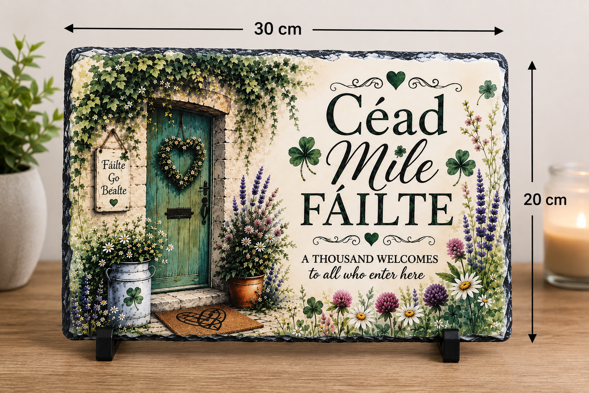 A rectangular decorative slate sign on a wooden surface, shown with dimension arrows indicating 30 cm by 20 cm. The sign features a vintage-style green door, floral borders, shamrocks, and the text 'Céad Mile Fáilte' and 'A THOUSAND WELCOMES to all who enter here.